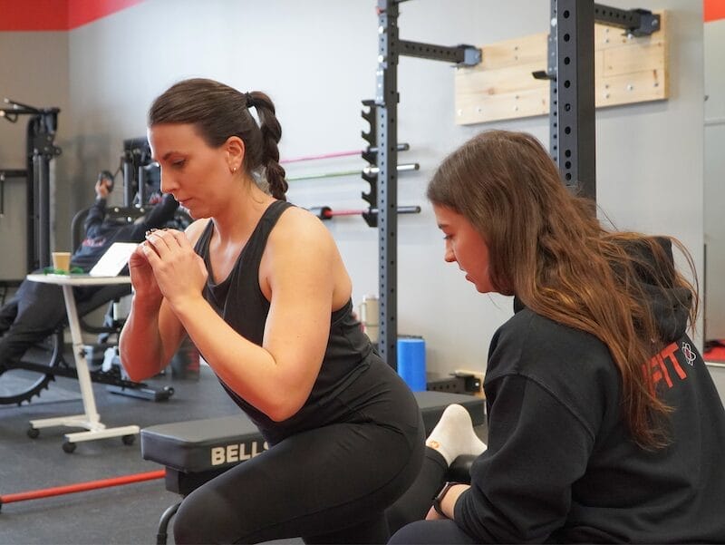 Un entraîneur personnel démontrant un squat dans un gym privé à Montréal.