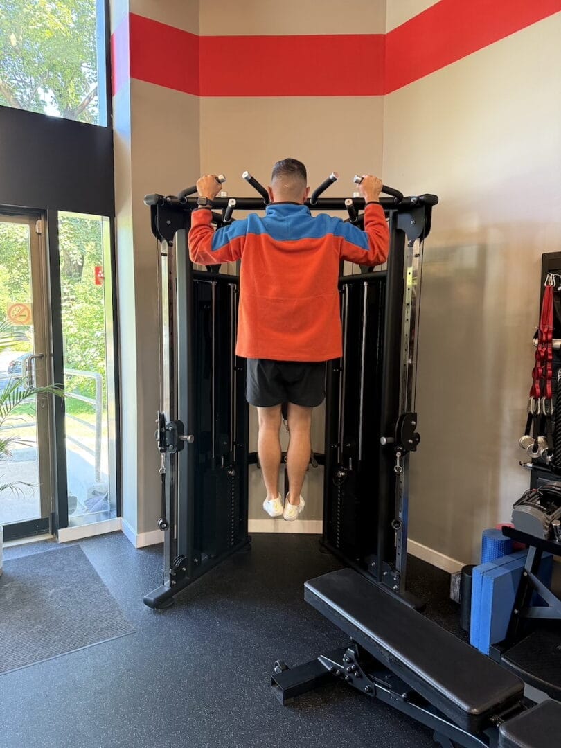 Un client de Studio Fit U travaillant avec un entraîneur personnel en train de faire une traction.